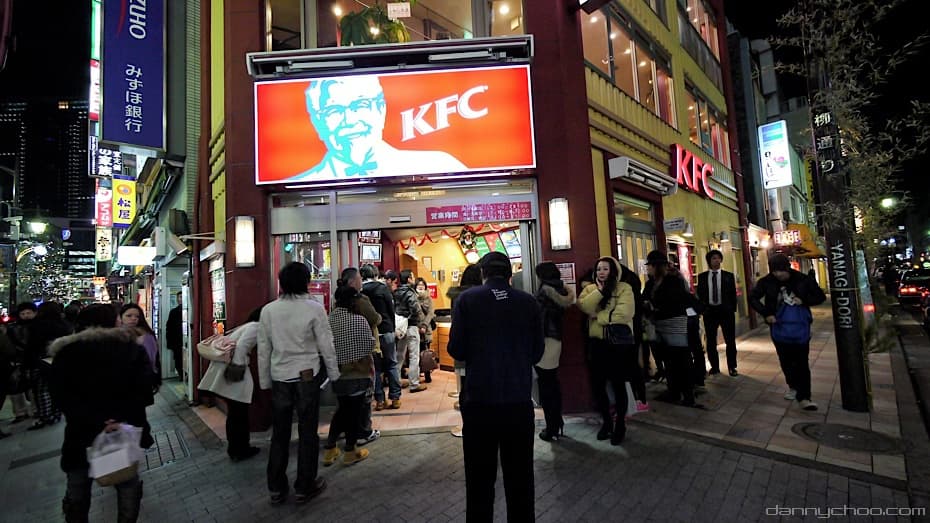 Menschen stehen in einer langen Schlange vor einem KFC-Restaurant auf einer Stra&szlig;e in Tokio w&auml;hrend Weihnachten im Jahr 2010.