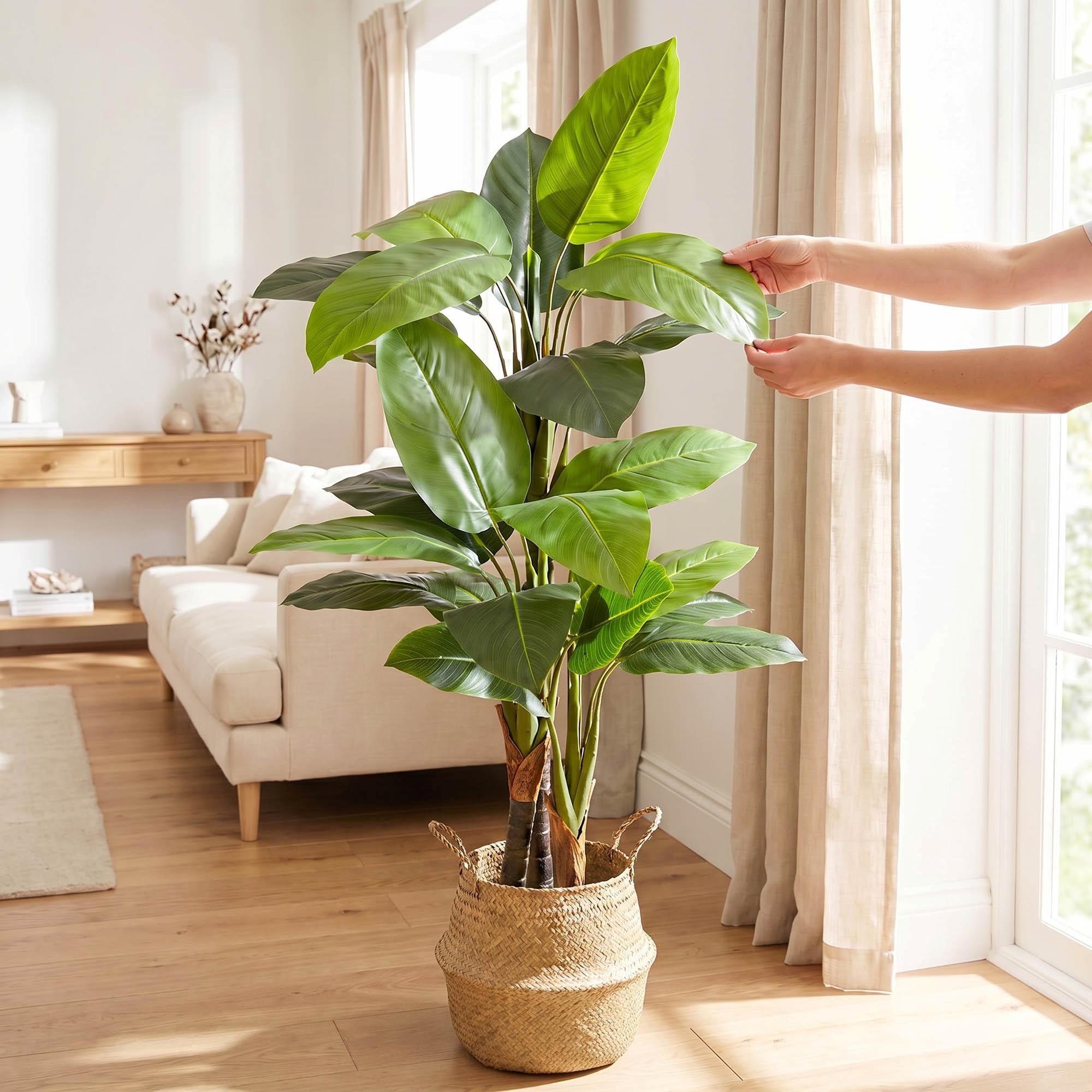 H&auml;nde richten die Bl&auml;tter der k&uuml;nstlichen Monstera auf einem 160 cm hohen Stiel von FairyTrees aus und betonen so ihr nat&uuml;rliches Aussehen und ihre Flexibilit&auml;t.
