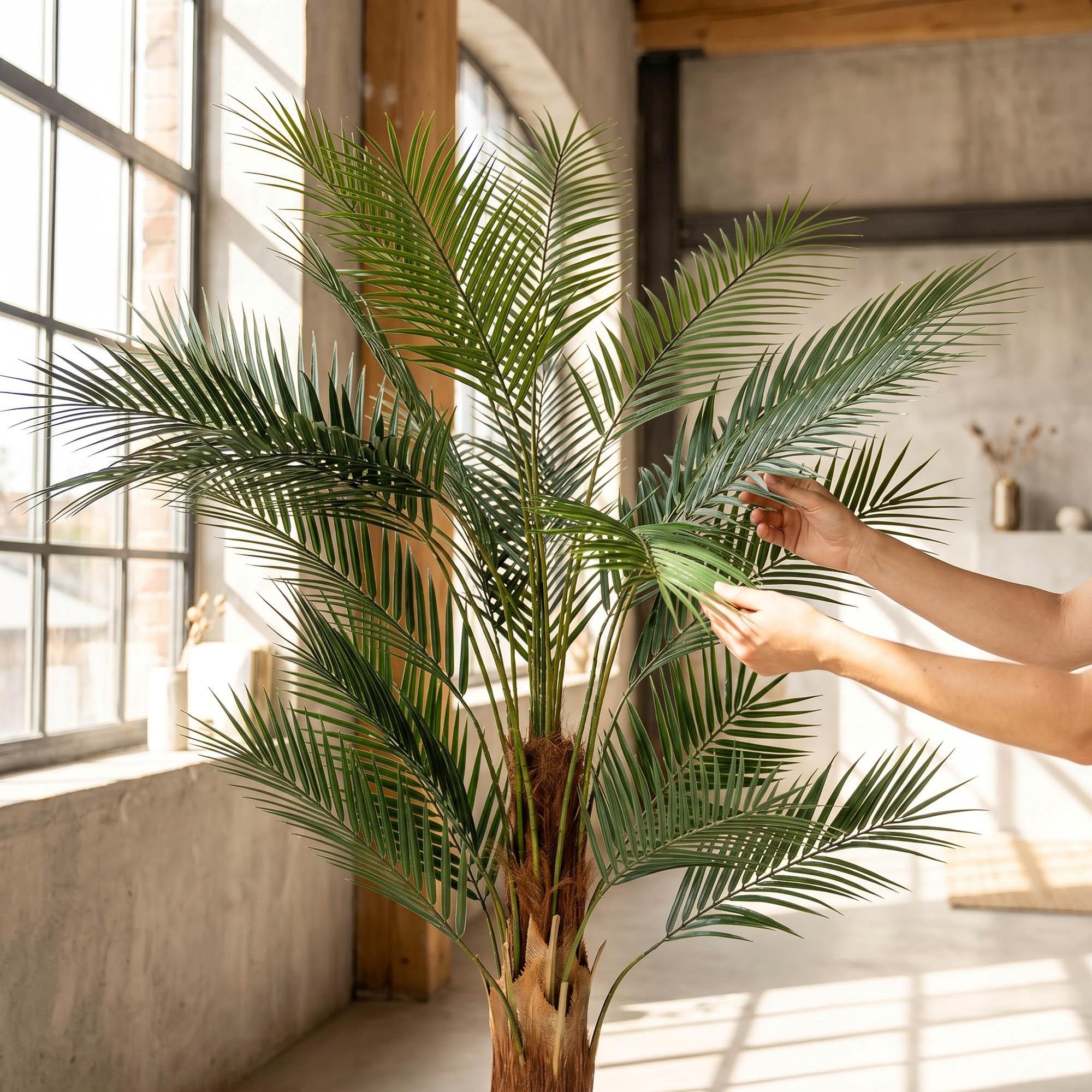 H&auml;nde richten die Bl&auml;tter der k&uuml;nstlichen Monstera auf einem 160 cm hohen Stiel von FairyTrees aus und betonen so ihr nat&uuml;rliches Aussehen und ihre Flexibilit&auml;t.