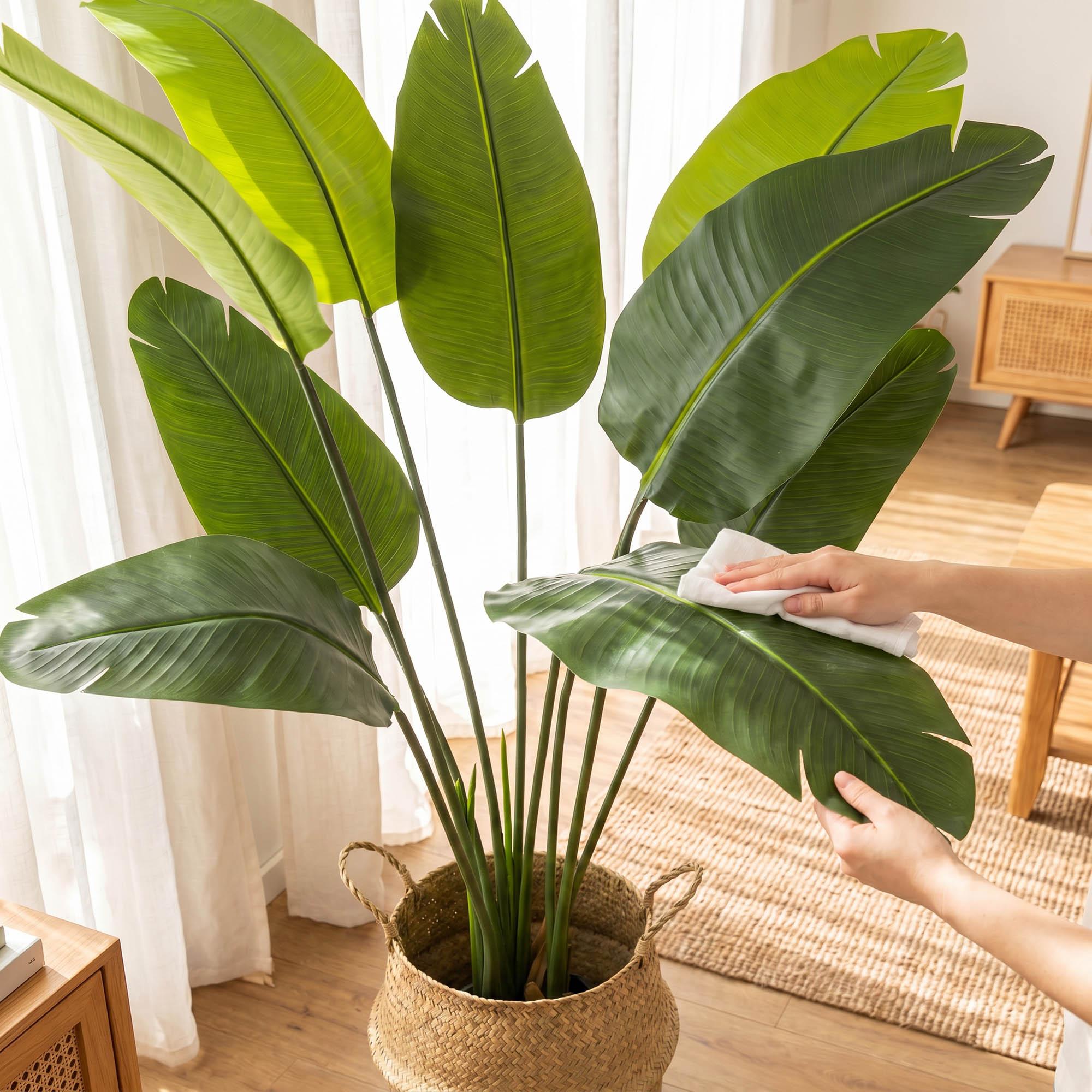 Die H&auml;nde reinigen die Bl&auml;tter der k&uuml;nstlichen Monstera am 160 cm hohen Stiel von FairyTrees und zeigen damit, wie pflegeleicht die Pflanze ist.